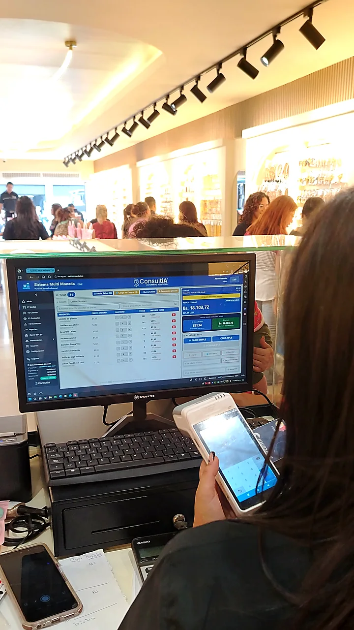 Cajera de Kavalier 24 cobrando con el Sistema Multi Moneda, con la tienda al fondo